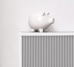 White pig piggy bank on radiator. Expensive heating costs concep Heizen mit Strom ist günstiger als gedacht