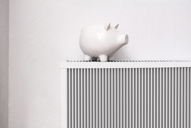 White pig piggy bank on radiator. Expensive heating costs concep